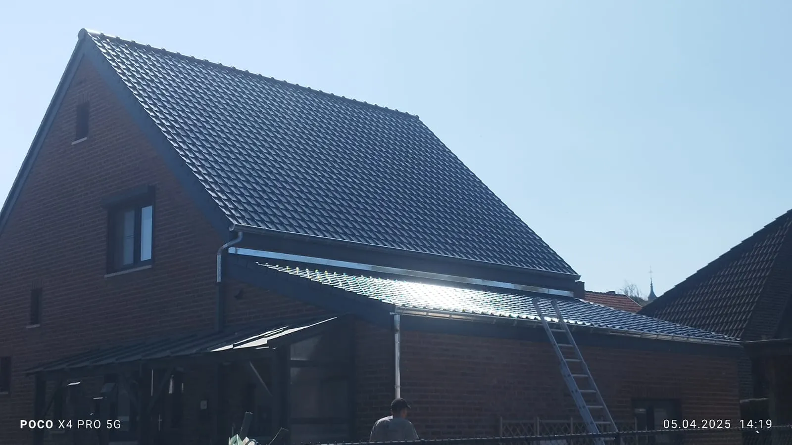 Zijaanzicht van een woning in Hoegaarden met een donker pannendak en isolatieplaten op het lagere dak.
