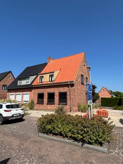 Voorgevel van een bakstenen woning met een oranje pannendak en twee dakkapellen met lichte bekleding.