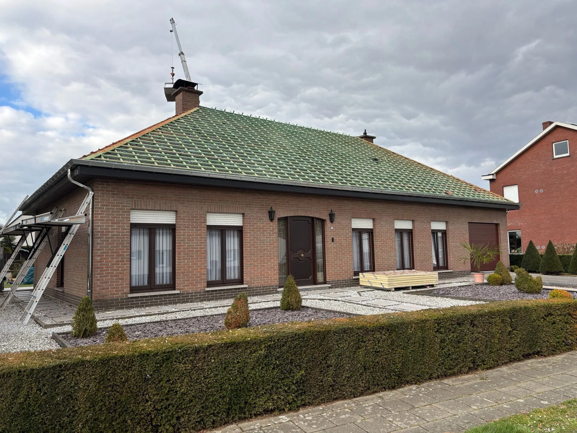 Woning tijdens dakrenovatie met groene onderdakfolie en panlatten op het schilddak.