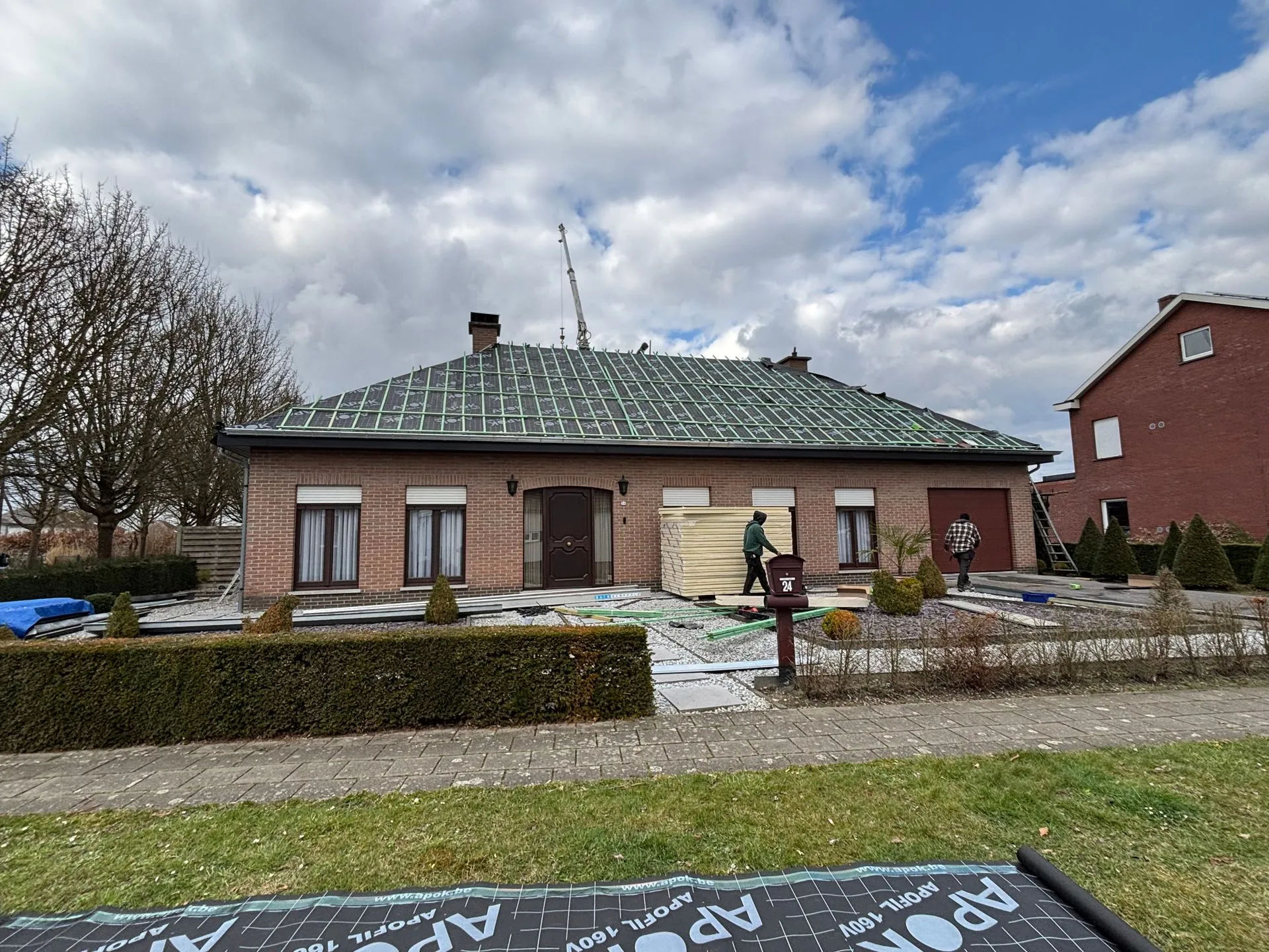 Overzicht van een dakrenovatie met onderdakfolie, panlatten en stapels isolatieplaten voor de woning.