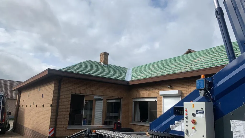 Dak van een woning in Lummen tijdens renovatie, met groene onderdakfolie en een hijskraan naast de gevel.