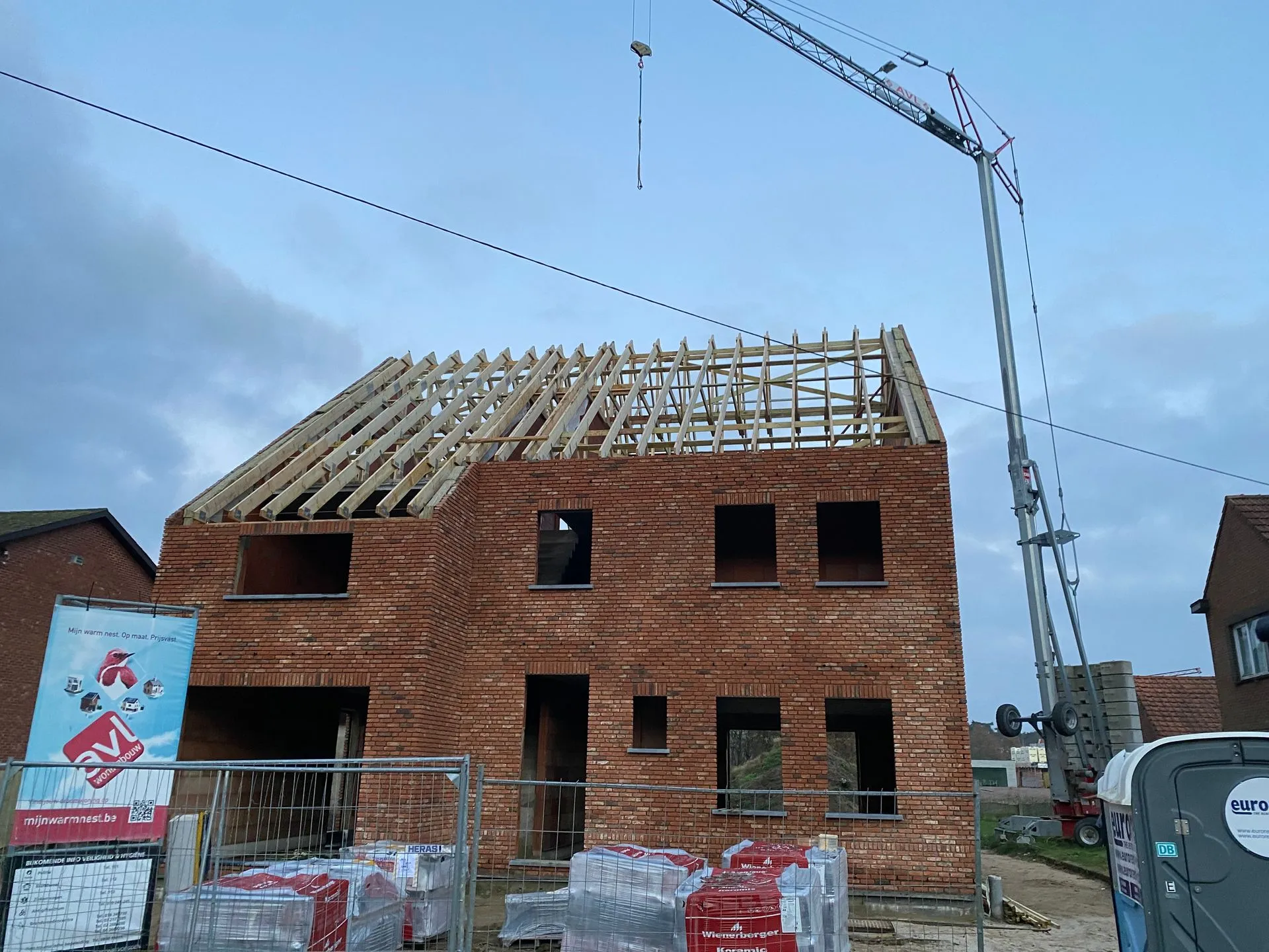 Woning in aanbouw in Averbode met zichtbare houten dakspanten en een bouwkraan naast de ruwbouw.